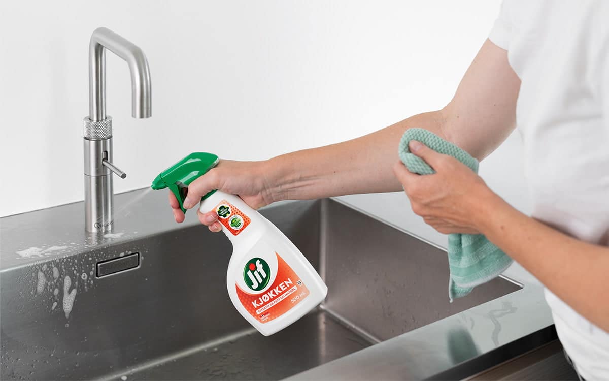 Kvinne vasker med Jif Kjøkken Spray for å unngå bakteriebomber på kjøkkenet.