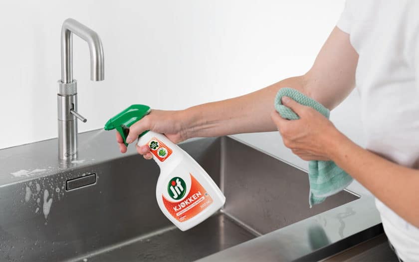 Kvinne rengjør oppvaskkummen med Jif Kjøkkenspray.