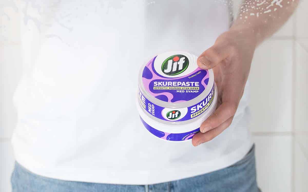 Mann vasker dusjdørene med Jif Skurepaste.
